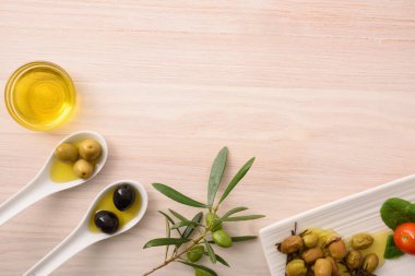Yemek için farklı zeytin çeşitleri ve ahşap mutfak tezgahındaki kaplarda yağ. Üst görünüm.