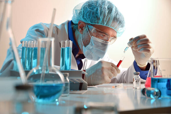 Microbiologist mixing reagent with sample in laboratory. Horizontal composition. Front view.