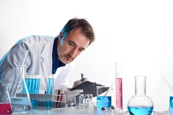 Scientist writing in a notebook on a laboratory table with glassware and white isolated background. Horizontal composition. Front view.