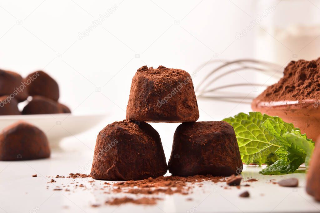 Preparing chocolate truffles with cocoa powder on kitchen bench with ingredients. Front view. Horizontal composition.