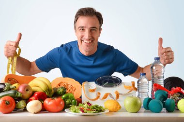Sağlıklı gıda ve spor aksesuarları sunan dietisyen sporcu, mavi izole bir geçmişe sahip ağırlık kontrolü ve sağlık için mezura ve mezura kullanıyor.