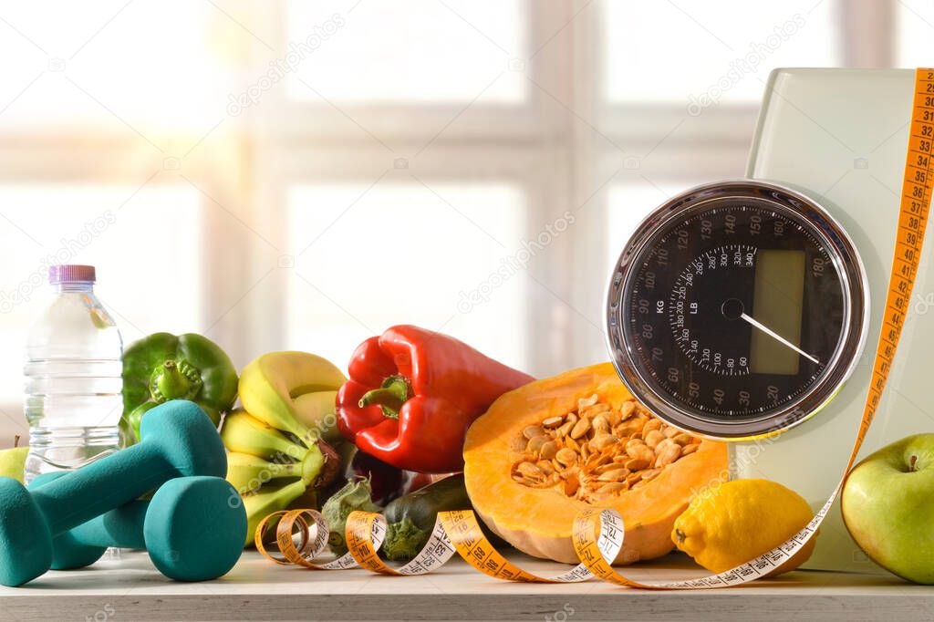 Healthy food and sport background on a white wooden table with scale and measuring tape with window background. Front view. Horizontal composition.