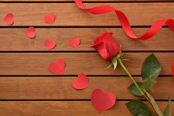 Kırmızı gül ve tahta tahta sehpada kalp şeklinde kırmızı kesikli romantik bir arkaplan. Üst görünüm.