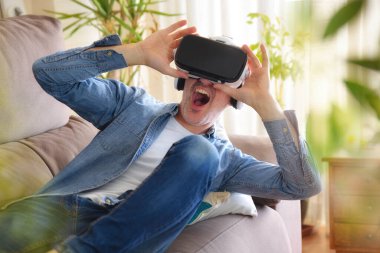 Sanal gerçeklik gözlüklü, evdeki kanepede uzanmış büyüleyici bir adam.