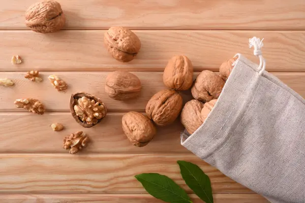 Group Walnuts Spilling Out Cloth Sack Seeds Leaves Wooden Table — Stock Photo, Image