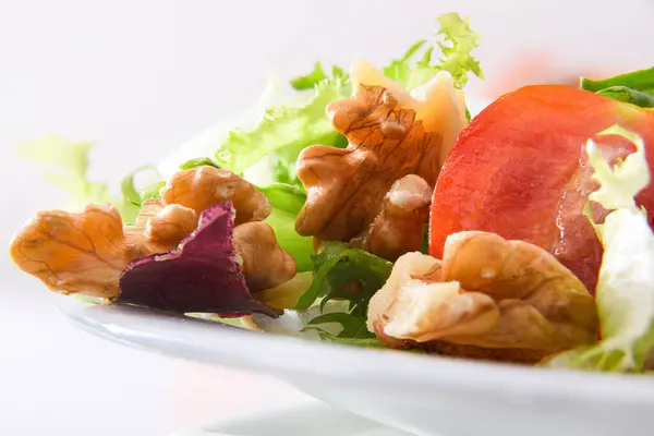 白いテーブルの上にレタストマトと玉ねぎとオリーブオイルとボウルにクルミと地中海サラダ隔離された背景 正面図 — ストック写真
