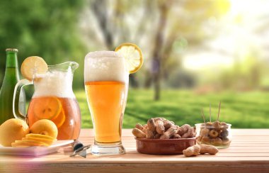  Kırsaldaki ahşap masada limonlu bir bardak bira ve abur cubur. Ön görünüm.