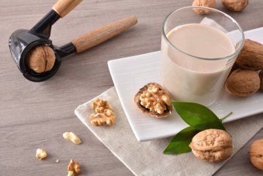 Meyveli fındık ve fındık dolu bir bardak dolusu sebze sütü ve fındık kıracağıyla ahşap masa. Yüksek görünüm.