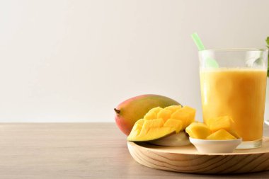 Mutfak tezgahında süt ve kesilmiş meyve arkaplanı olan doğal mango suyu. Ön görünüm.