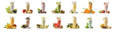 Beyaz masa ve beyaz izole arka planda çeşitli meyvelerle süslenmiş uzun bardakta kremalı milkshake seti. Ön görünüm.