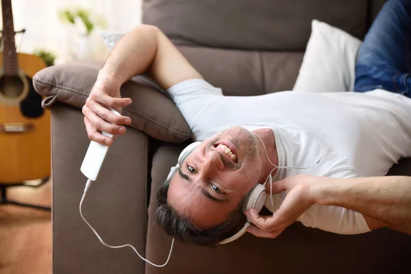 Hombre Feliz Divertido Tumbado Sofá Espalda Escuchando Música Desde Móvil —  Fotos de Stock