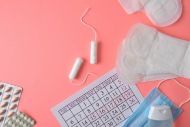 Regl ürünleri, haplar ve takviminde pembe arka plandaki kadınlar için kritik günler olan kişisel hijyen. Üst görünüm.