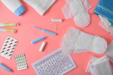 Çeşitli adet hijyen ürünleri, haplar ve pembe arka plandaki kadınlar için kritik günler takvimi olan kişisel hijyen. Üst görünüm.