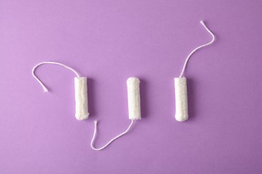 Leylak arka planında kadın bakımı için üç yumuşak koruyucu ve emici pamuk tampon. Üst Manzara. Yatay bileşim.