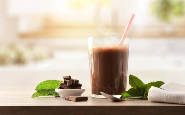 Çikolatalı milkshake ve çikolatalı süt. Mutfaktaki ahşap bankta. Ön görünüm.