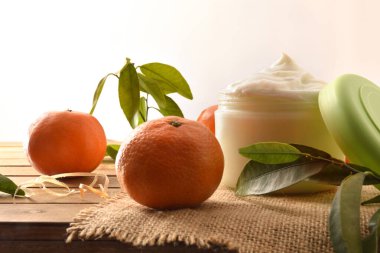 Mandalina özü, meyve ve ahşap masa yapraklı doğal cilt kremi. Ön görünüm.