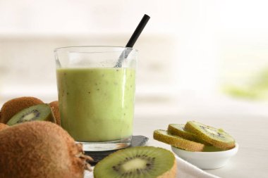 Bir bardak kivi içkisi ve konteynır mutfak tezgahında meyve kesiyor. Ön görünüm.