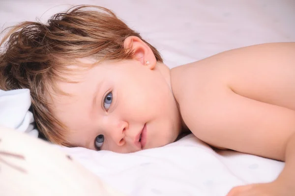 Blue eyed little girl lying on the bed — Stock Photo, Image