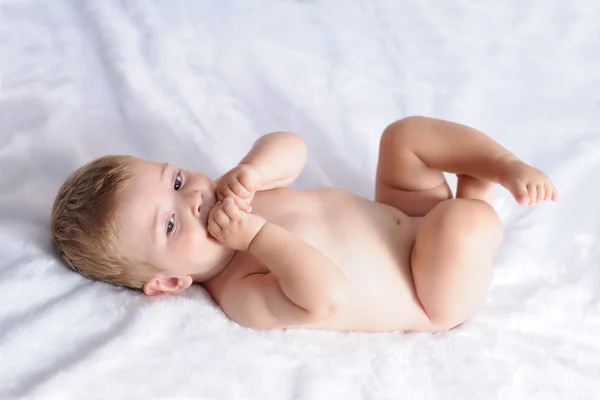 Baby biting hands on a blanket of white hair — Stock Photo, Image