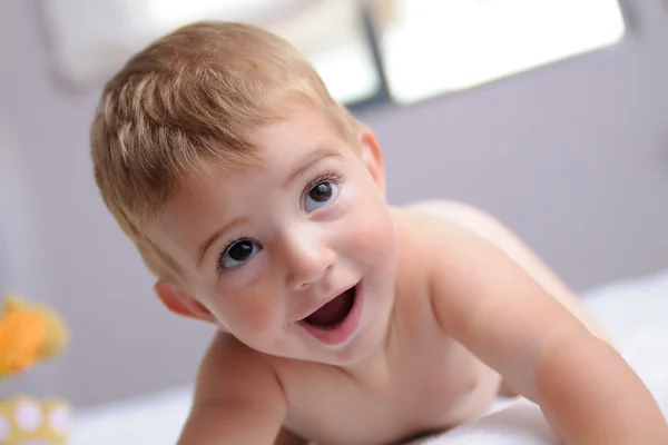 Vrolijke blond baby op een bed — Stockfoto