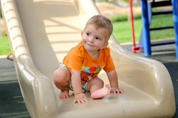 Little blond boy on a slide in the park — Stock Photo, Image