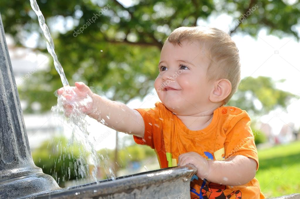 blonde boy playing with water fountain