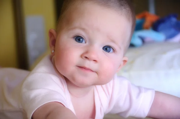 Vrouwelijke baby met roze lichaam op het bed — Stockfoto