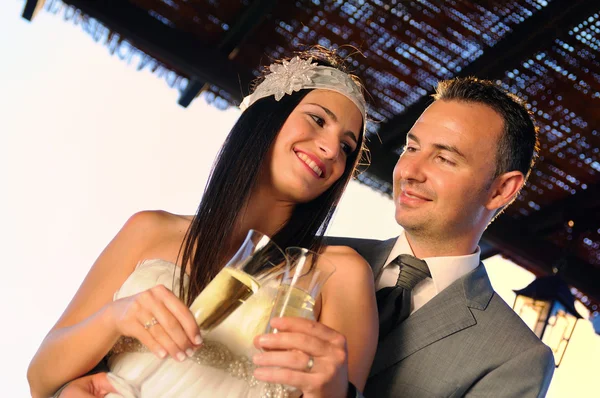 Groom and bride toasting on a terrace smiling eye contact — Stock Photo, Image