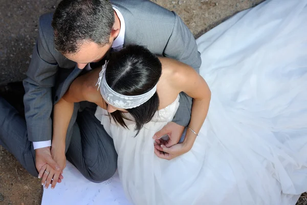 Groom porra mãos da noiva sentado no chão — Fotografia de Stock