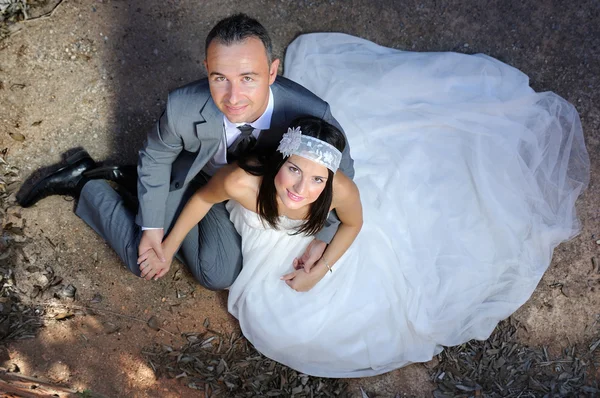 Groom and bride holding hands sitting on the floor — Stock Photo, Image