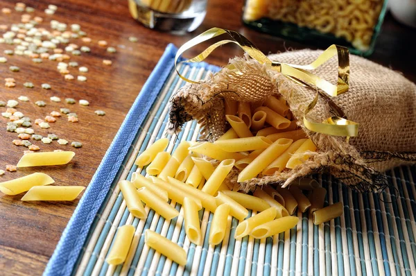 Ongekookt macaroni samenstelling uit een jute zak — Stockfoto