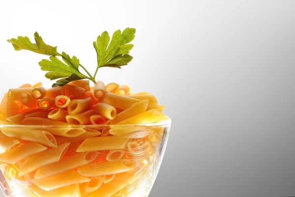 Uncooked macaroni into a boll of glass — Stock Photo, Image