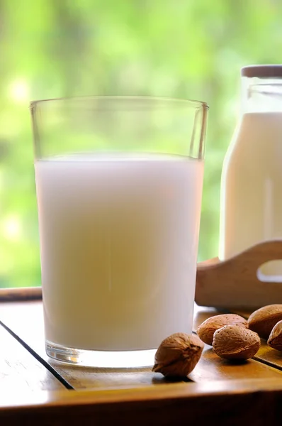 Стакан миндального молока на столе с миндалем переднего вида крупным планом — стоковое фото