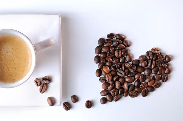Coração com grãos e xícara de café — Fotografia de Stock