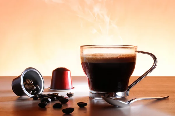 Capsules and cup of hot espresso coffee — Stock Photo, Image