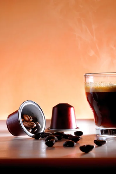 Capsules and cup of hot espresso coffee close up — Stock Photo, Image