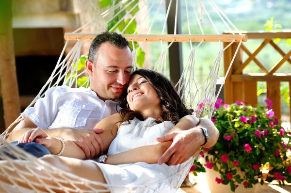 Young couple on a rope hammock in a cottage — Stock Photo, Image