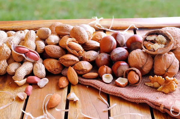 Tasty nuts on a wooden table in field — Stock Photo, Image