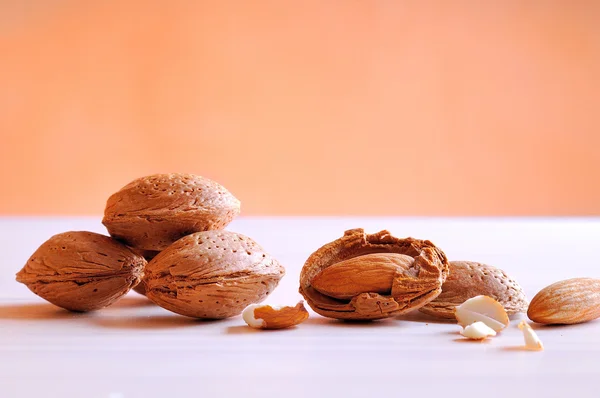 Amandes sur une table blanche et fond orange — Photo