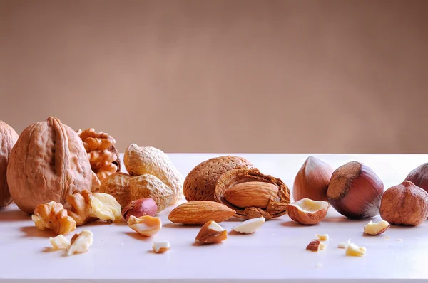 Tasty nuts in shell and shelled on a white table — Stock Photo, Image
