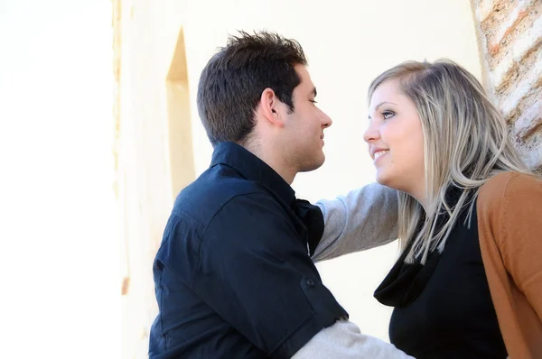 Flirting couple against a brick wall in park bottom view