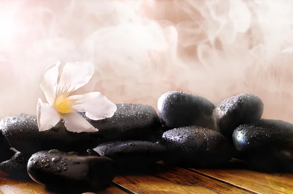 Group of black stones on wood base with steam background