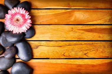 Black stones and flower on the left side on wooden