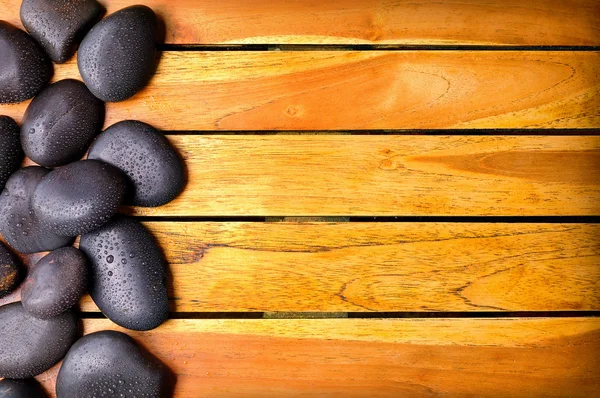 Pedras com gotas de água no lado esquerdo em madeira — Fotografia de Stock