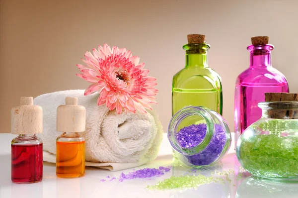 Oils and bath salts on white table with brown background — Stock Photo, Image