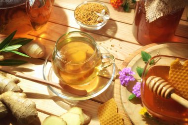 Honey and ginger infusion in a glass cup on a wooden table with natural products from organic farming as alternative medicine. Elevated view.