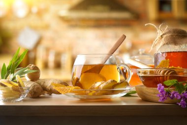 Freshly prepared ginger and honey infusion on a wooden bench with ginger roots, jars of honey, and a rustic kitchen background. Front view.