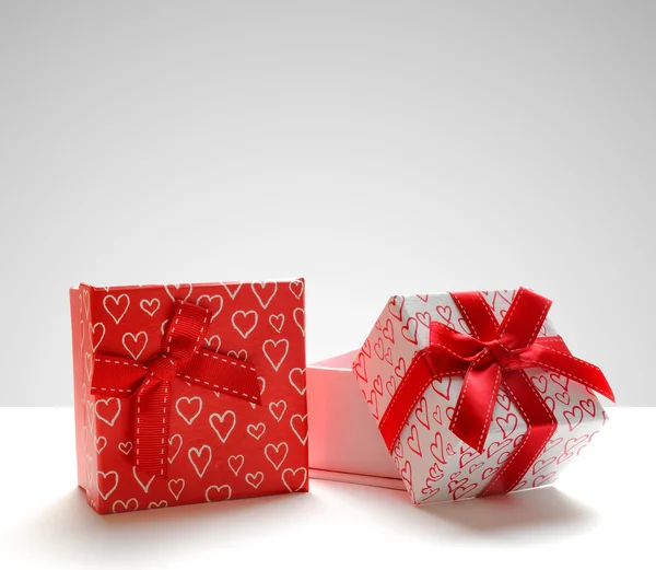 Две подарочные коробки с напечатанными сердцами на сером фоне — стоковое фото