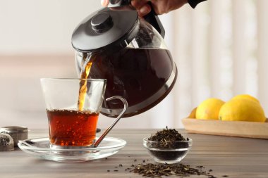 İnsanlar bir kase dolusu çay yaprağı ve parlak bir mutfakta limonlu bir tepsiyle ahşap bir bankta çay servisi yapıyorlar. Ön görünüm.