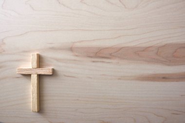 Hafif doğal ahşap bir yüzeye yumuşak tahıl dokusuyla asgari ahşap haç yerleştirilmiş. Kopya alanı olan temiz kompozisyon, Hıristiyanlığın, inancın ve ruhaniliğin sembolü.